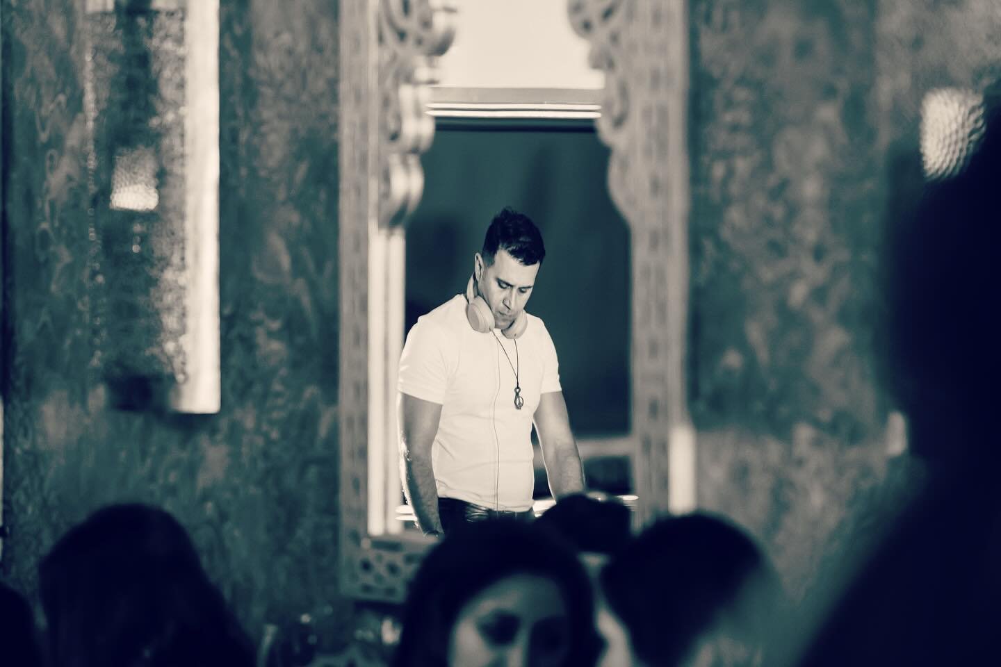 Black-and-white portrait of DJ Alphire with headphones at an event venue.