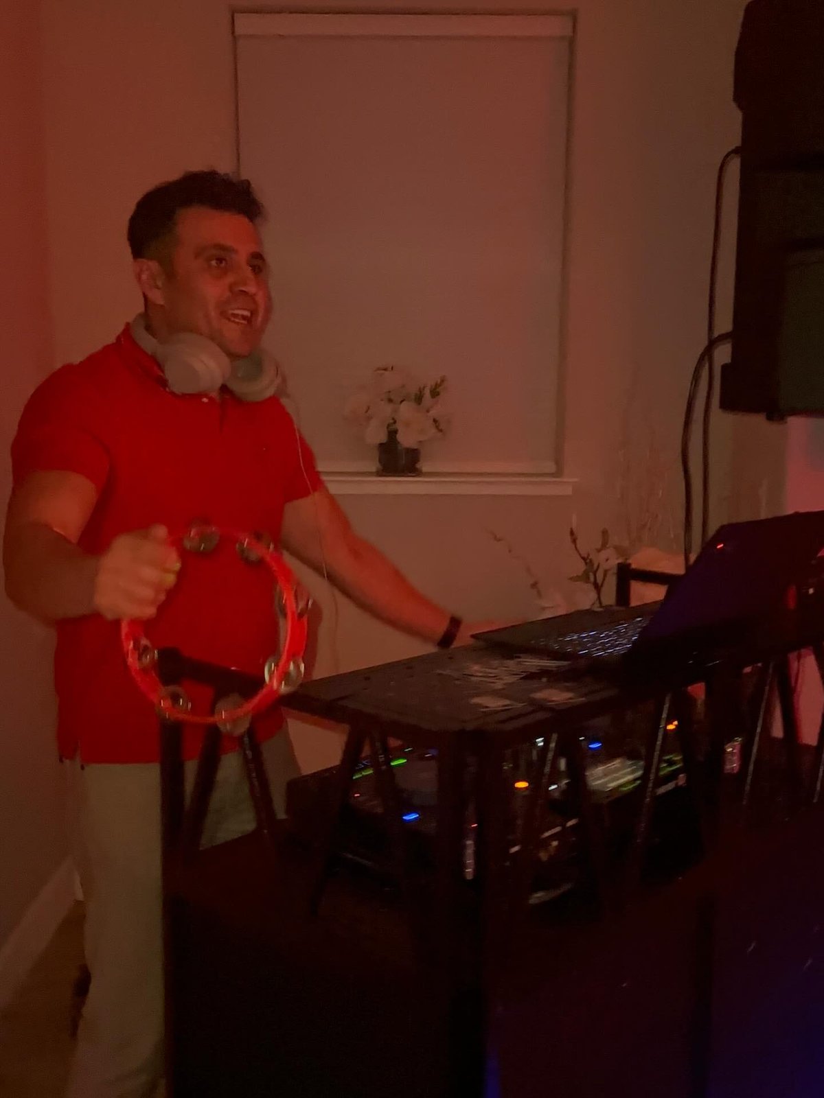 DJ Alphire hyping the crowd with a tambourine behind his DJ setup