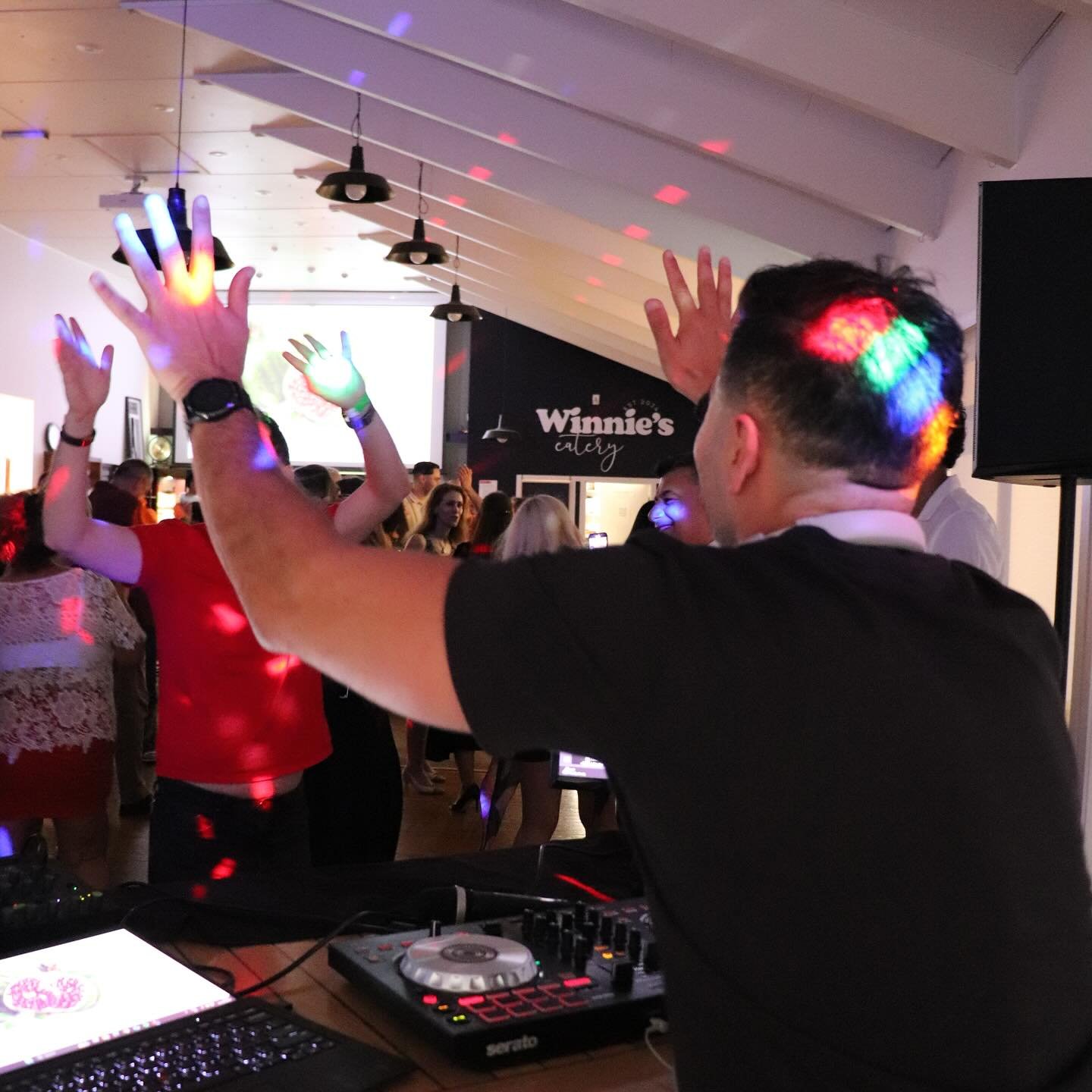 DJ Alphire behind the decks with hands raised at a Bay Area event