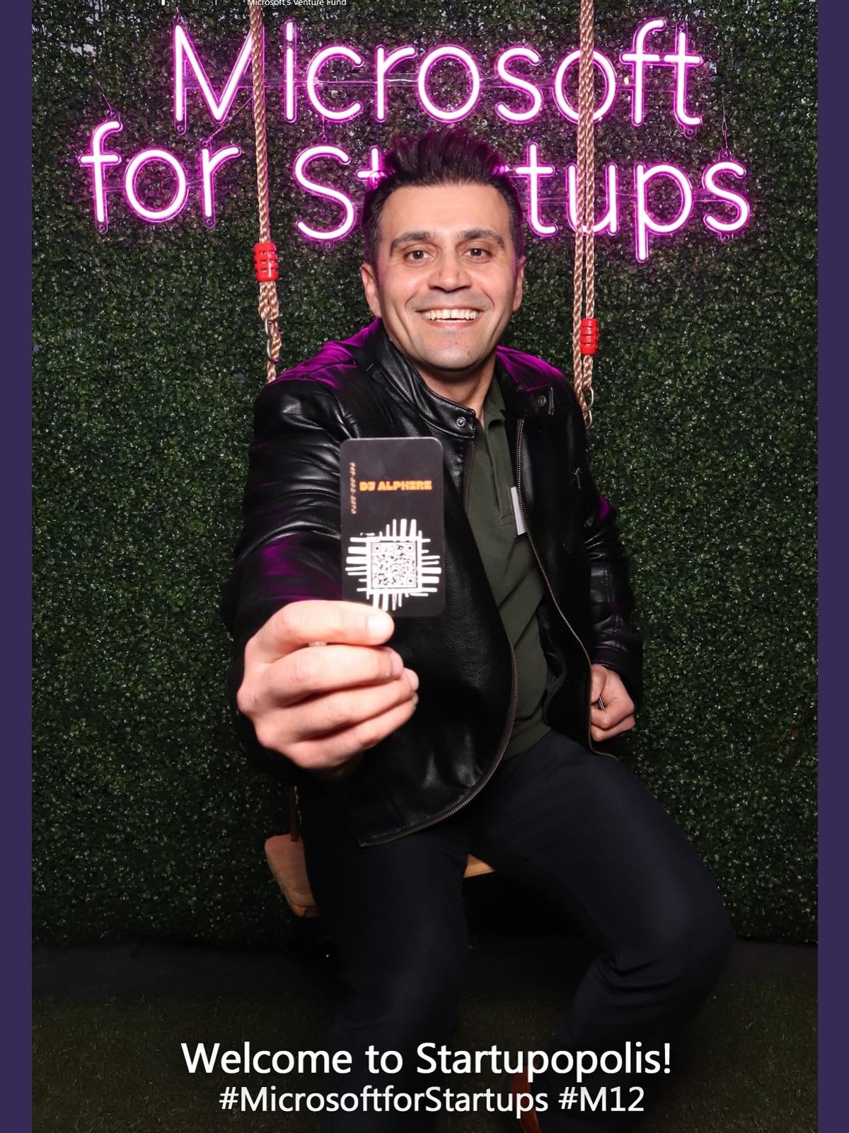 DJ Alphire smiling at a networking event holding his business card