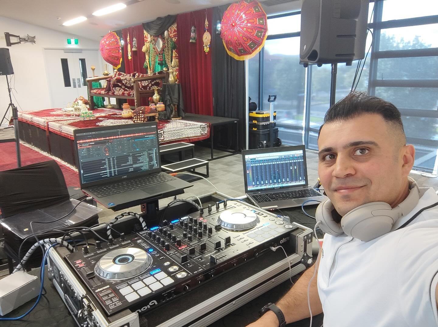 DJ Alphire behind his Pioneer DJ controller and laptops at a decorated wedding celebration.