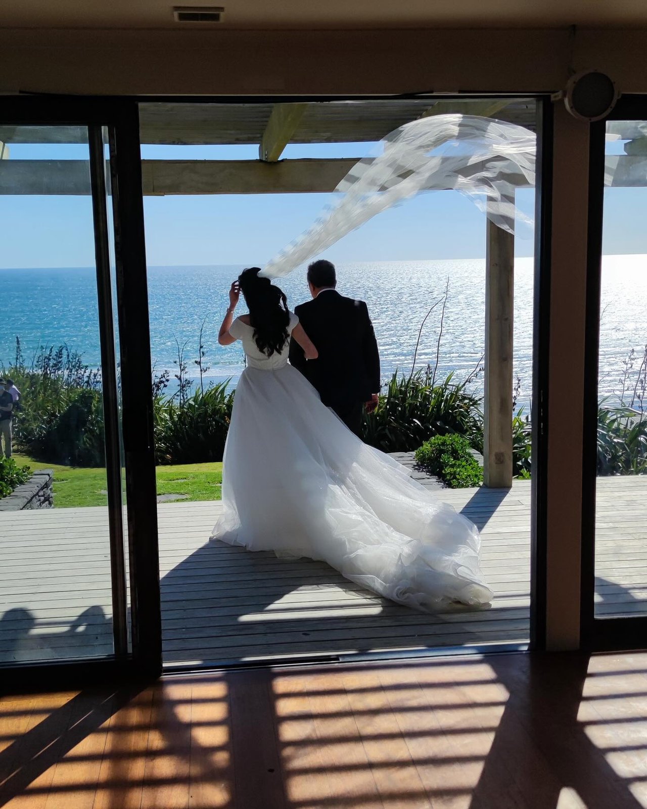 Bride and groom taking in the ocean view at a beachfront wedding reception.