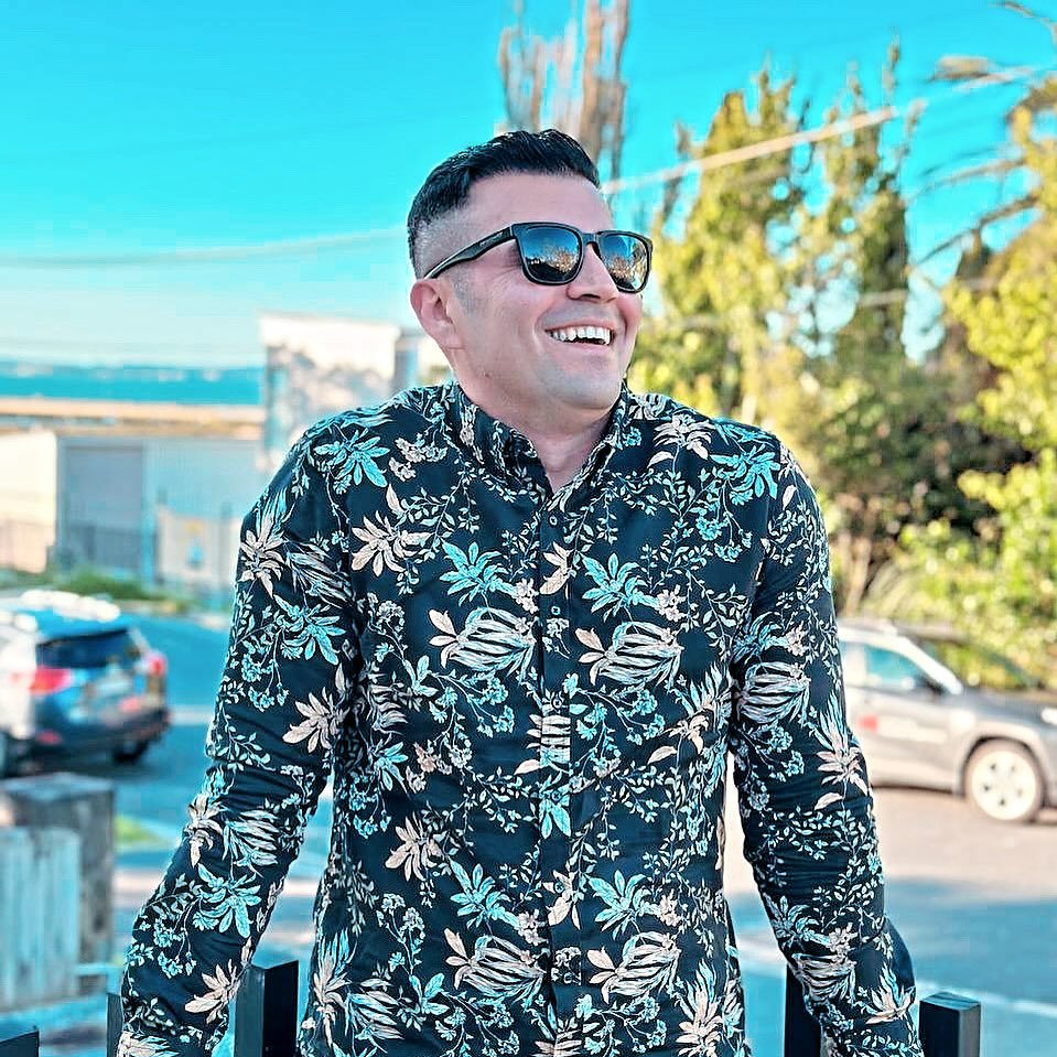 DJ Alphire smiling in a casual outdoor portrait.