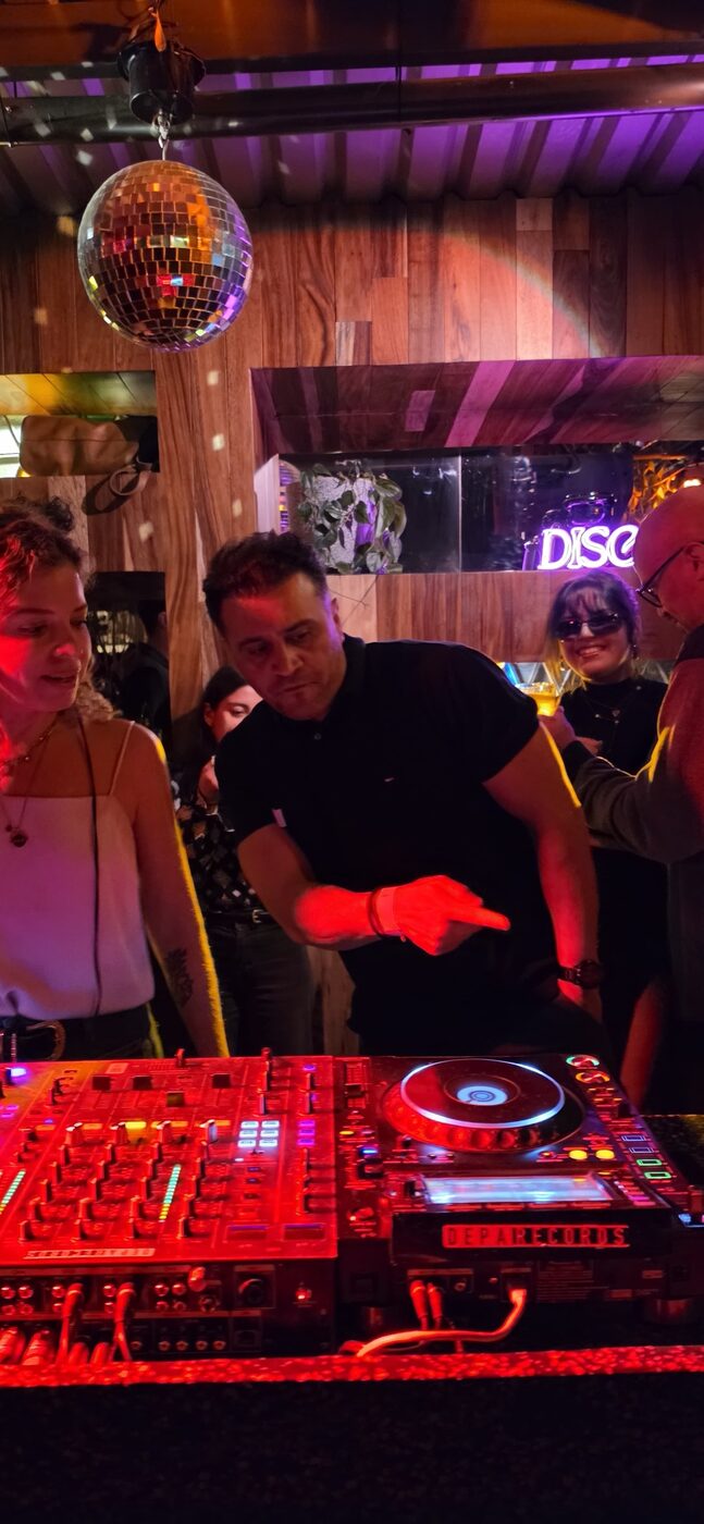 DJ Alphire's Pioneer Rekordbox setup at an outdoor daytime event with guests