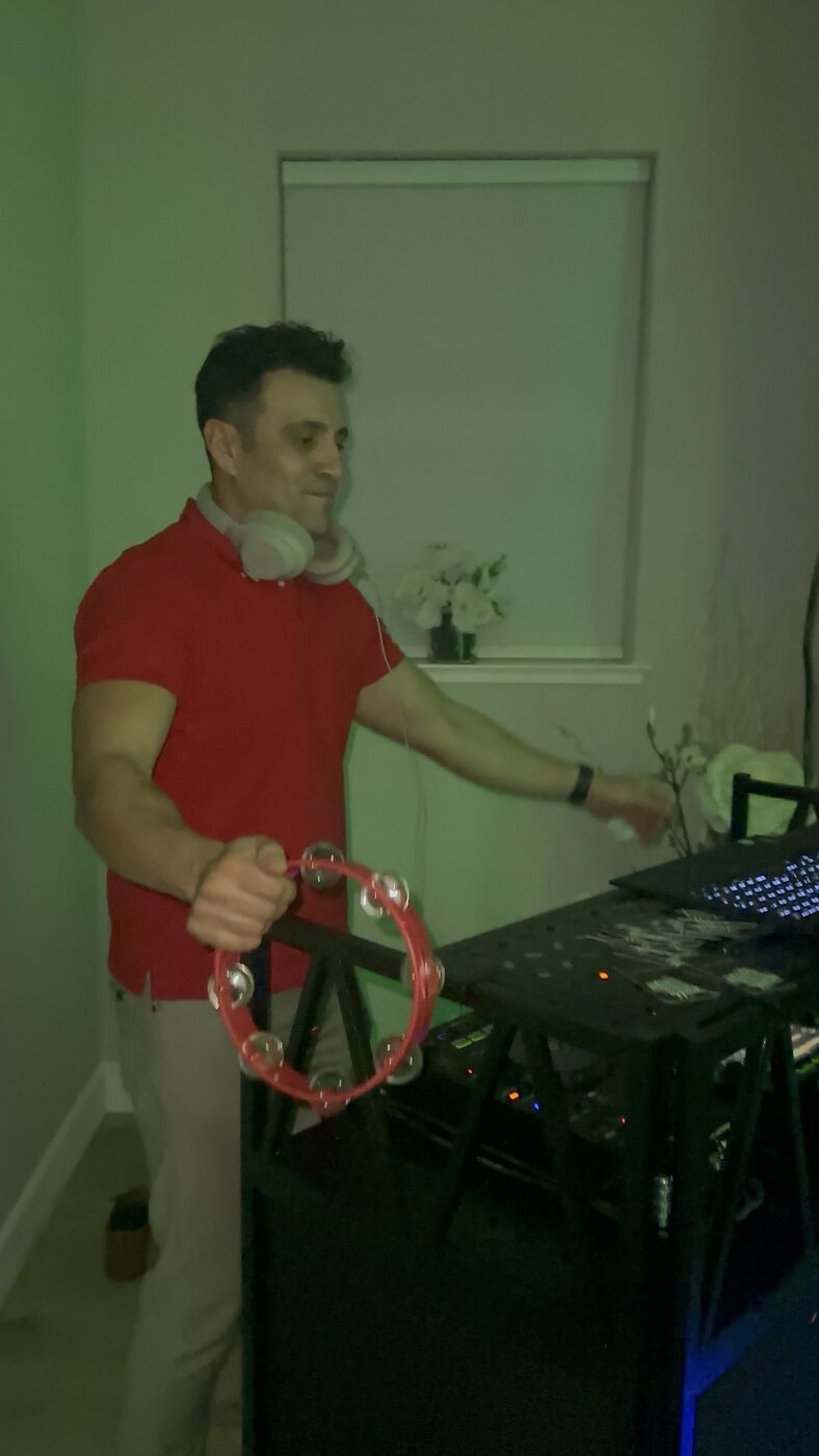 DJ Alphire performing under purple stage lighting at an indoor event