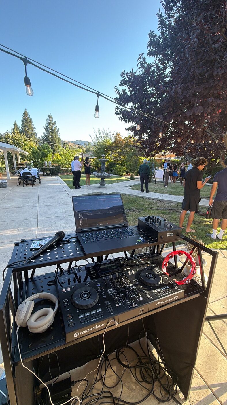 DJ Alphire's setup at an indoor networking event with crowd in background