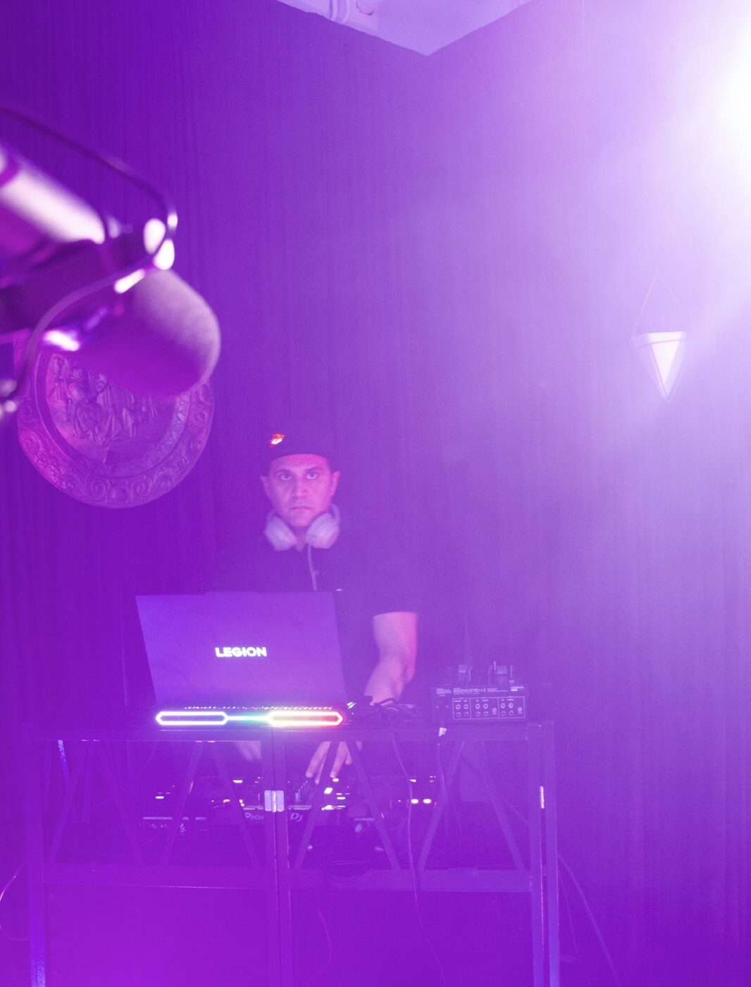 DJ Alphire under purple club lighting with Lenovo Legion laptop and Pioneer DJ gear